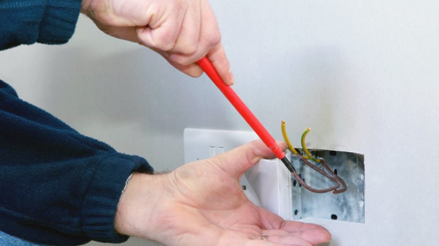 Electrician wiring a double socket with an insulated screwdriver